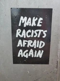 A black and white sticker with the text "Make Racists Afraid Again" written in white paint on a black background.