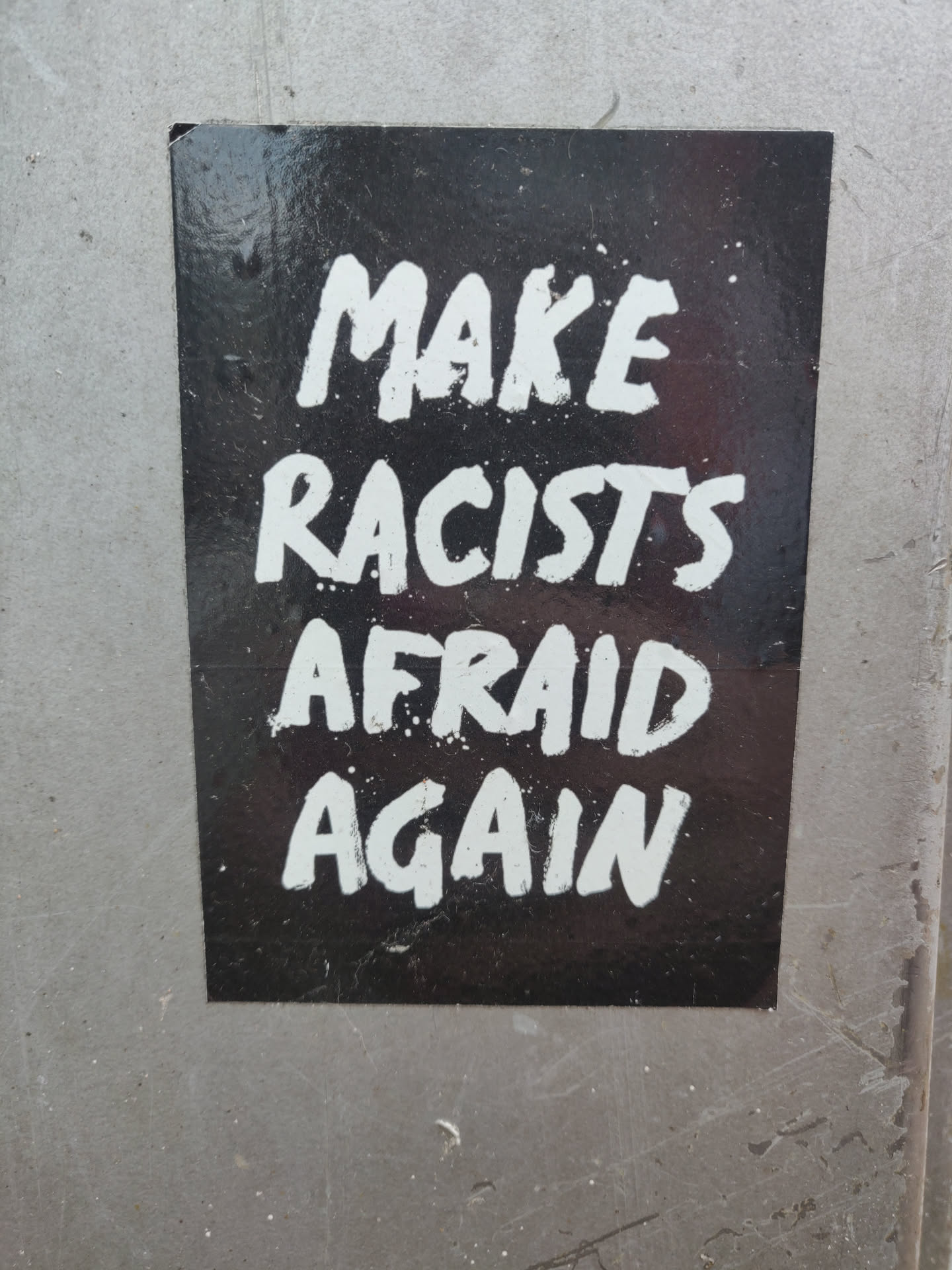 A black and white sticker with the text "Make Racists Afraid Again" written in white paint on a black background.