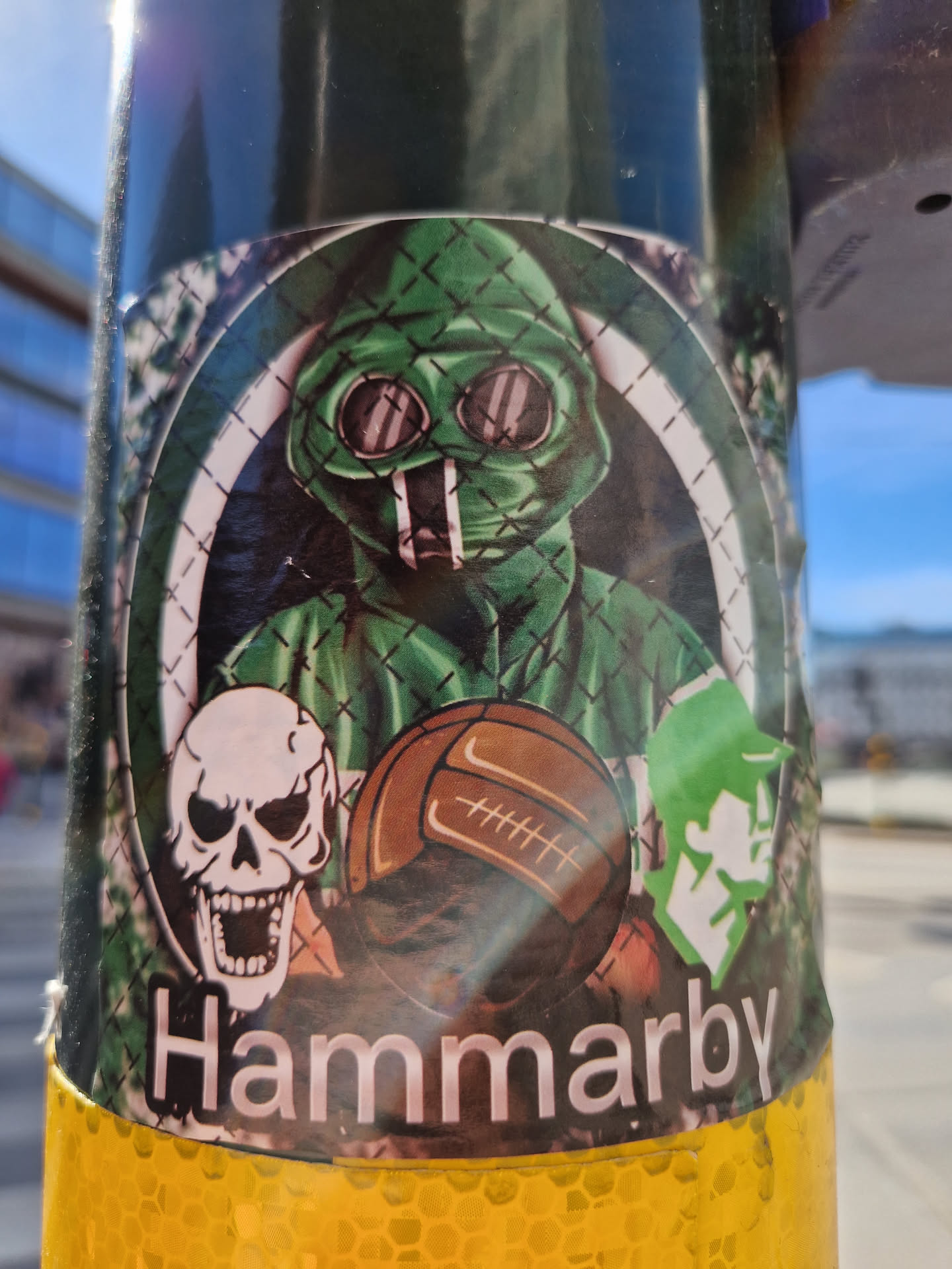 A sticker depicting a person in a green gas mask, along with a skull and a football. The word Hammarby is written at the bottom of the sticker.