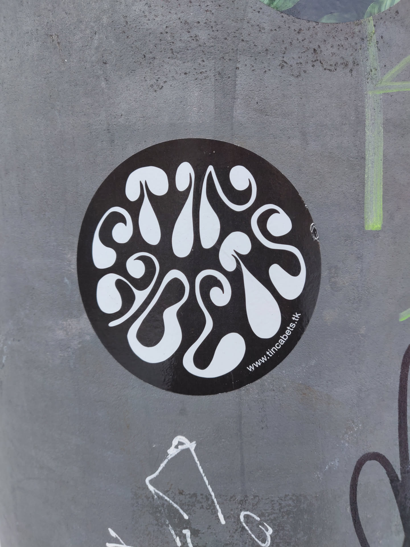 A round black and white sticker with an abstract design. The design features white organic shapes on a black background.  The text at the bottom reads 'www.tincabels.tk'.