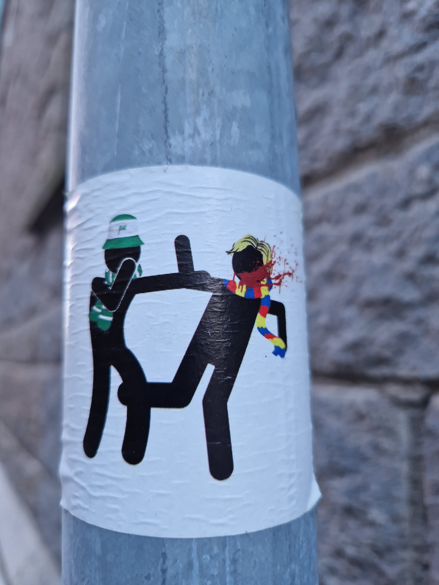 This sticker shows a violent scene between two stick figures, one representing Celtic FC (based on the hat) and the other seemingly representing Romania (based on the scarf colors). The image is provocative and possibly alludes to political or football-related conflict.