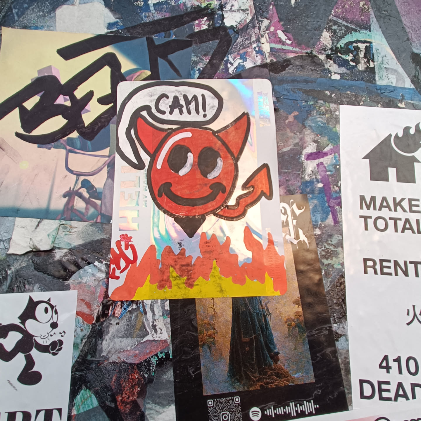 Holographic sticker of a smiling devil character with flames at the bottom. The devil is red and has a speech bubble saying "Can!"