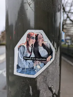 A sticker featuring a photo of two women, likely in Stockholm, Sweden.  The sticker has a slightly damaged appearance.