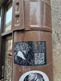 Black and white sticker with the word "Threadbare" and an illustration. It also mentions that it's a free to use second hand luxury clothing aggregator. A QR code is present at the right side. 