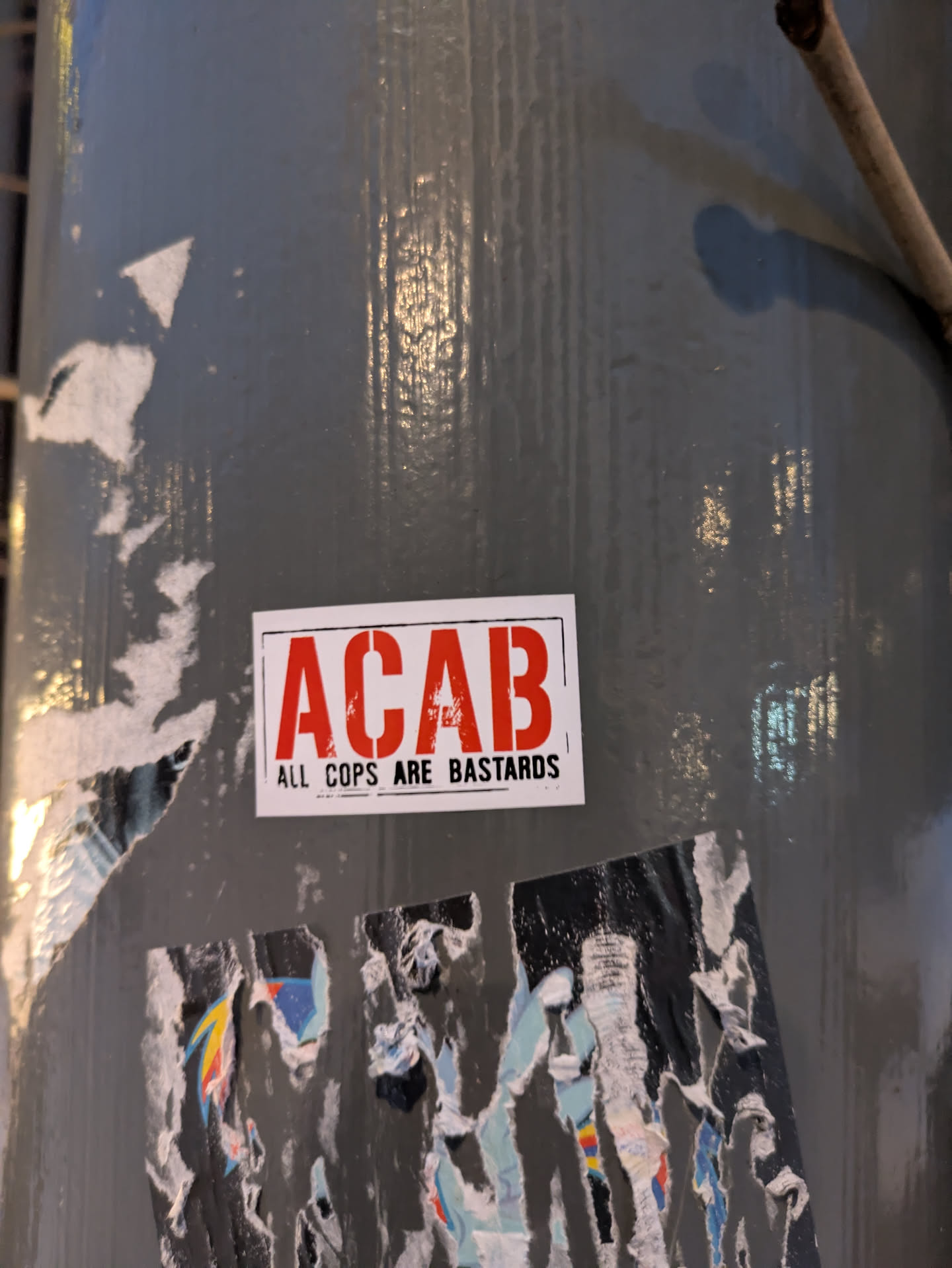 A red and white sticker with the acronym ACAB and the words "All Cops Are Bastards" printed on it.